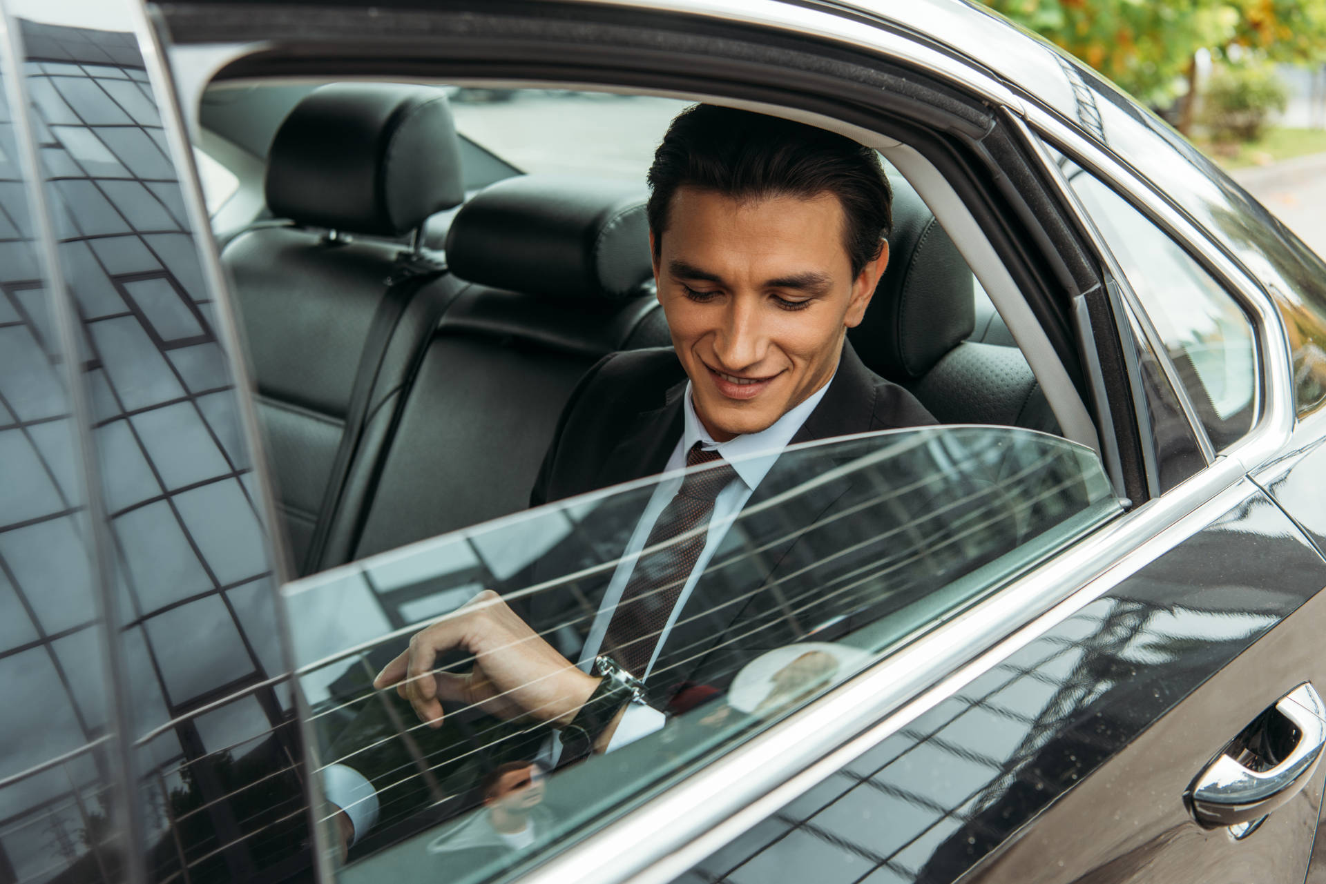 A business traveler in the back of a luxury car.