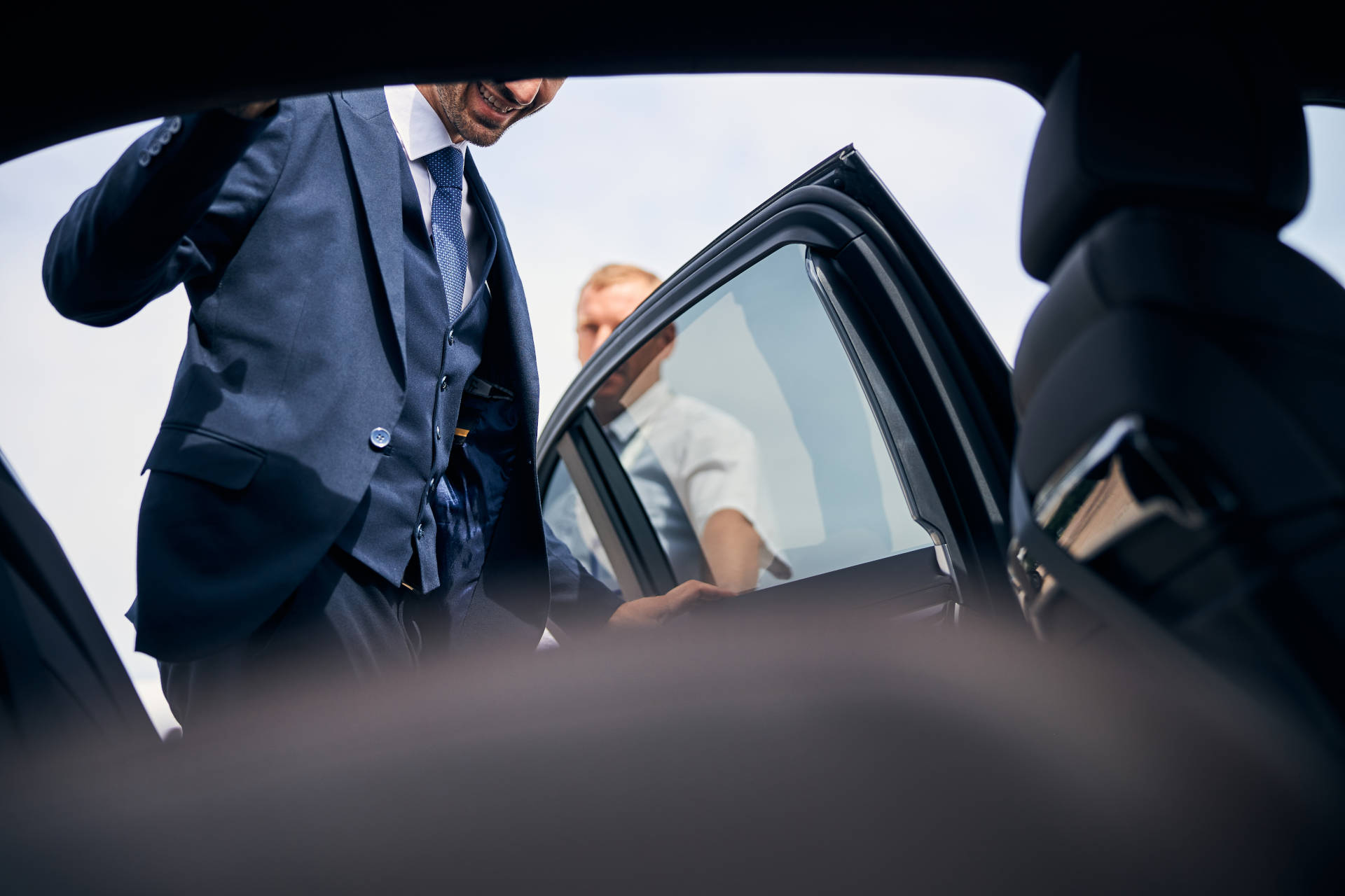 A business traveler getting into a luxury car